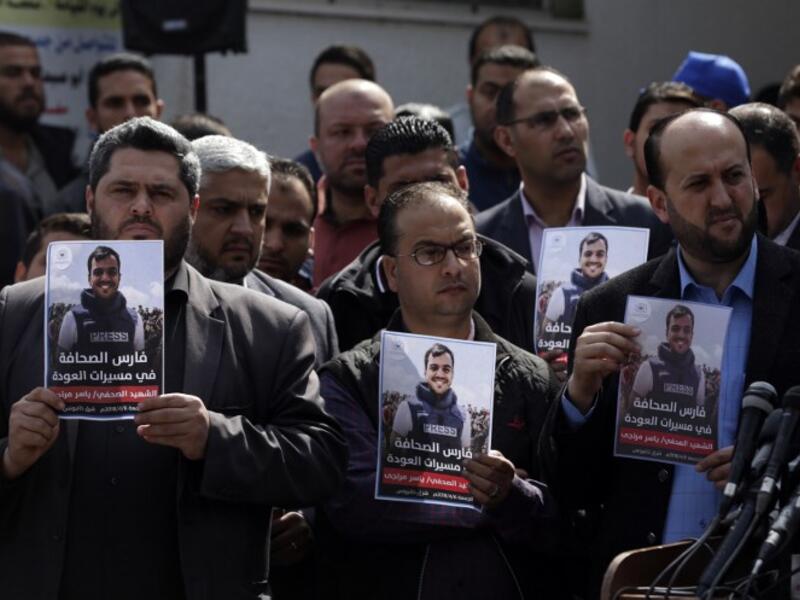 Palestinian journalists carry a portrait of journalist Yasser Murtaja, during his funeral in Gaza City on Apr. 7, 2018. (MAHMUD HAMS / AFP)