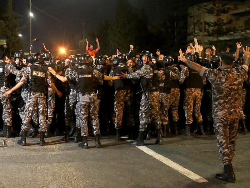Demonstrators confront anti-riot policemen as they protest against against a proposed income tax draft law in front of the Prime Minister's office in Amman, late on June 1, 2018. 
STRINGER / AFP