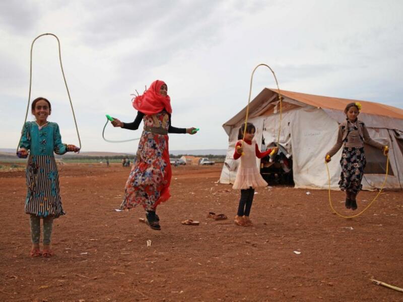 Syrian children who fled with their families from the northern countryside of Hama, jump rope in the yard of the makeshift school of "Zuhur al-Mustaqbal" (in Arabic "Flowers of the Future") in al-Jeneinah camp for displaced people in the village of Atme, in Syria's mostly rebel-held northern Idlib province, on October 1, 2018. Aaref WATAD / AFP