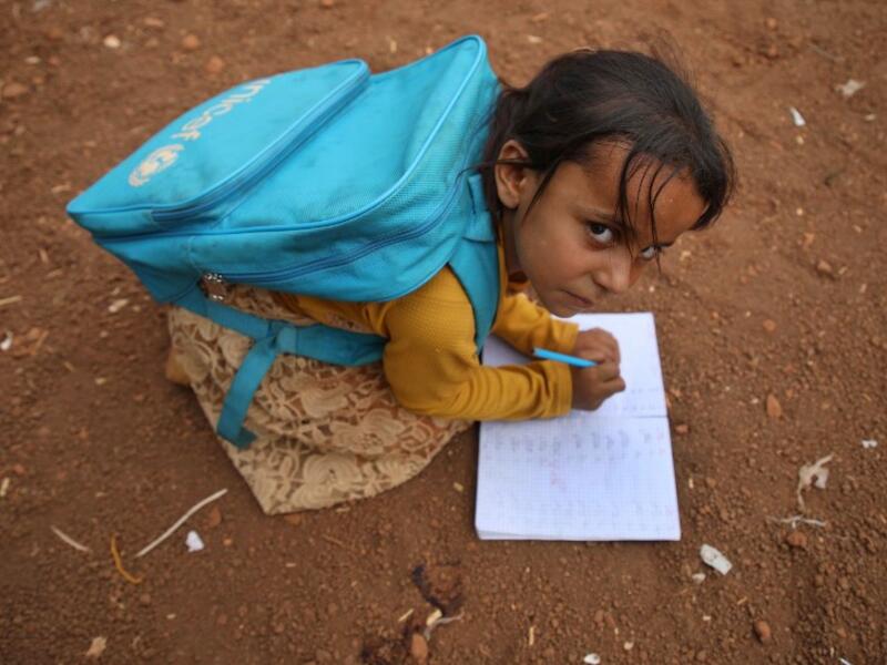 A Syrian child who fled with her family from the northern countryside of Hama, writes in a notebook in the yard of the makeshift school of "Zuhur al-Mustaqbal" (in Arabic "Flowers of the Future") in al-Jeneinah camp Aaref WATAD / AFP