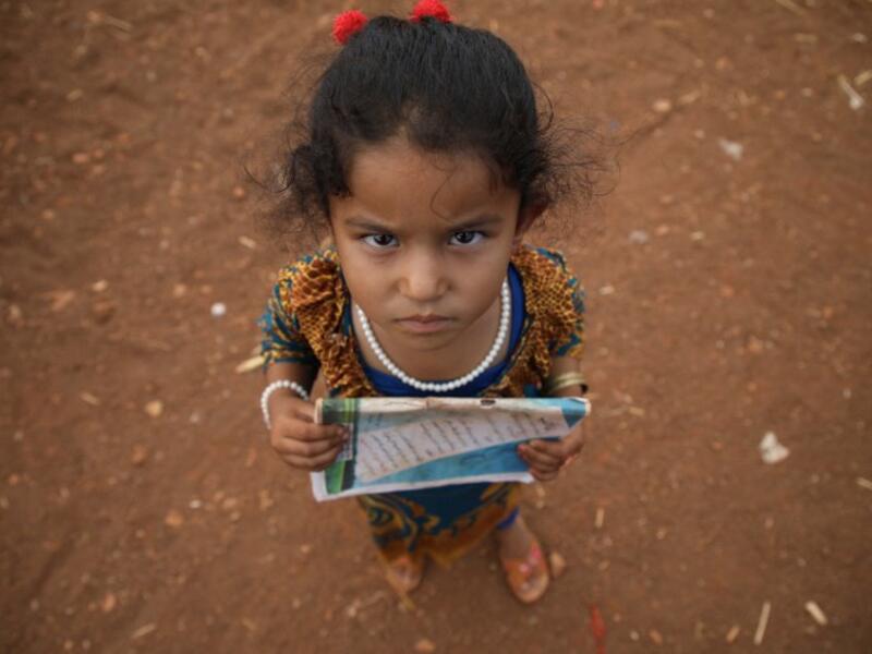 A Syrian child who fled with her family from the northern countryside of Hama, holds a book in the yard of the makeshift school of "Zuhur al-Mustaqbal" (in Arabic "Flowers of the Future") in al-Jeneinah camp for displaced people in the village of Atme, in Syria's mostly rebel-held northern Idlib province, on October 1, 2018. Aaref WATAD / AFP