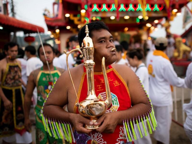 A devotee of the Loem Hu Thai Su shrine has a metal jug pierced through his cheek during the annual Vegetarian Festival in Phuket on October 12, 2018. Jewel SAMAD/AFP