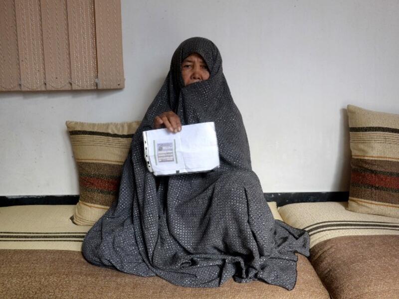 In this photo taken on October 11, 2018. Afghan housewife Fatimah, 55, poses for a picture as she holds her ID card or Tazkira registered to vote in the upcoming parliamentary election, at her House in Mazar-i-Sharif. 
FARSHAD USYAN / AFP