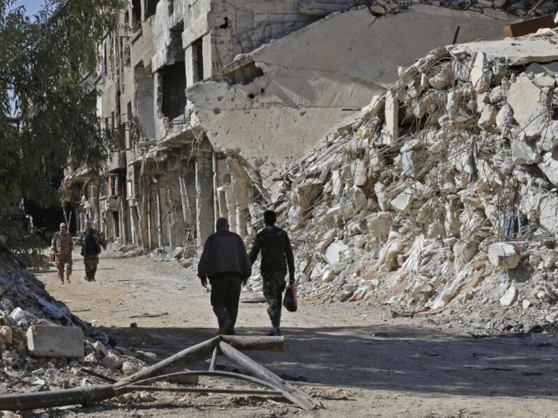 People walk past destroyed buildings in the Palestinian camp of Yarmuk southern Damascus on November 1, 2018. 
LOUAI BESHARA / AFP