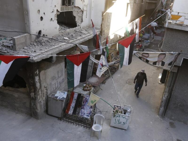 A man walks past destroyed buildings decorated with Palestinian flags in the Palestinian camp of Yarmuk southern Damascus on November 1, 2018. 
LOUAI BESHARA / AFP