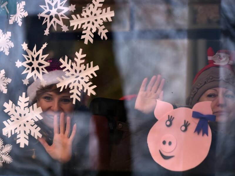 Women wave from a bus window during the New Year's car parade in the town of Vileyka about 100 km northwest from Russia's Minsk on December 29, 2018. 
Sergei GAPON / AFP