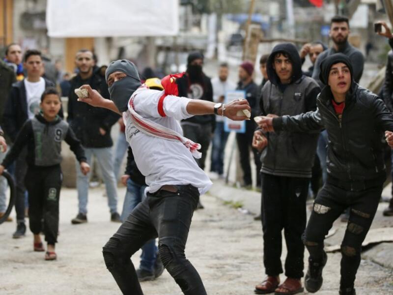 Palestinian protesters hurl stones at Israeli soldiers near a gate leading to Hebron's main al-Shuhada street. (AFP/ File Photo)