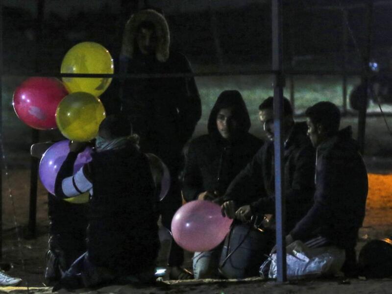 Palestinian protesters hold incendiary ballons that will be released over Israel, during a night demonstration near the fence along the border with Israel, in Rafah 
SAID KHATIB / AFP