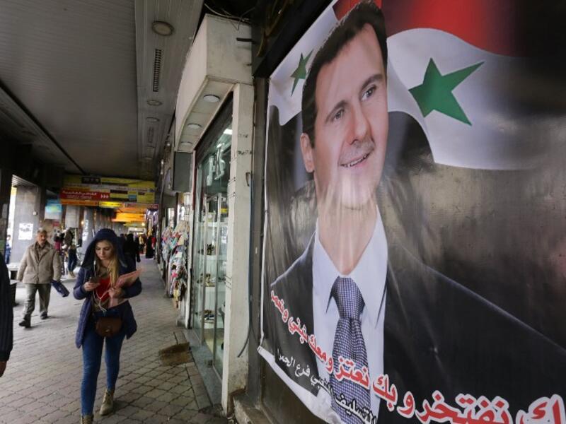 Syrians walk past a portrait of President Bashar al-Assad in the capital Damascus on March 15, 2016. (AFP/Louai Beshara)