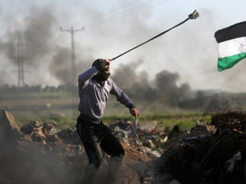 Palestinian protesters hurls a rock at Israeli security forces during clashes near the Shejaiya area of Gaza City along the border with Israel on December 18, 2015. (AFP/Mahmud Hams)
