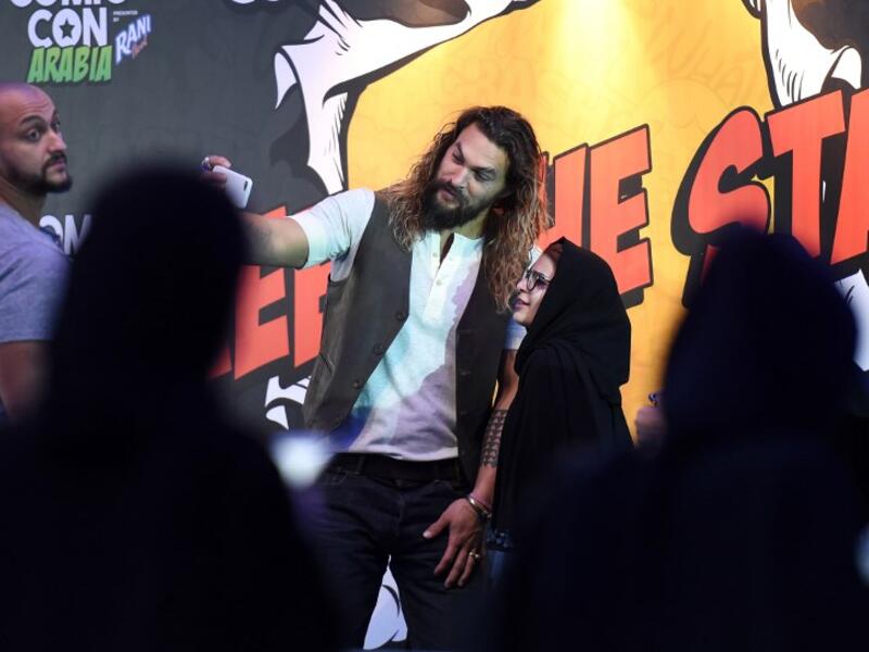 US actor Jason Momoa uses a cell phone to pose for a "selfie" photograph with a Saudi woman as they attend the first ever Comic-Con Arabia event held in the capital Riyadh on November 25, 2017. 
(FAYEZ NURELDINE / AFP)