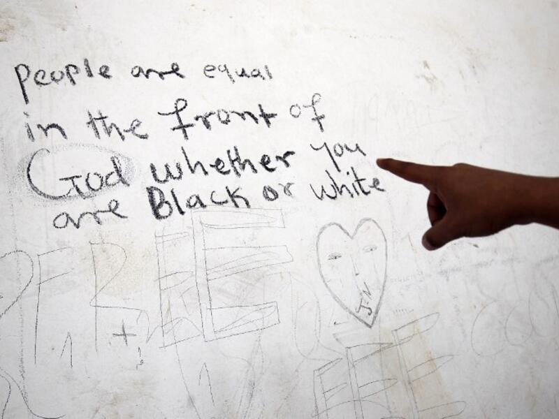 A sub-Saharan migrant shows writings on a wall as he waits at the Qanfouda detention center, in the southern outskirts of Benghazi, before being repatriated on Dec. 2, 2017. 
(Abdullah DOMA / AFP)