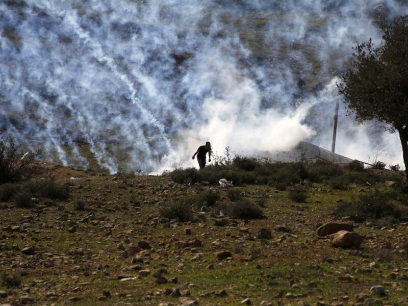 Palestinians run for covers from smoke-grenades during clashes with Israeli security forces following a demonstration in support of Palestinian prisoners on Jan. 13, 2018, in the West Bank village of Nabi Saleh (ABBAS MOMANI / AFP)