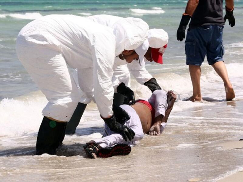 Members of the Libyan Red Crescent, wearing protective white clothing and masks, collect the body of a refugee that had washed ashore on a beach on August 28, 2015 in the port town of Zuwara. (AFP/File)