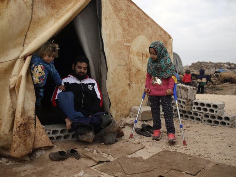 Maya Merhi (R) stands with the support of crutches next to her disabled father (C) outside their tent in the Internally Displaced Persons (IDP) camp of Serjilla in northwestern Syria next to Bab al-Hawa border crossing with Turkey.
Aaref WATAD / AFP