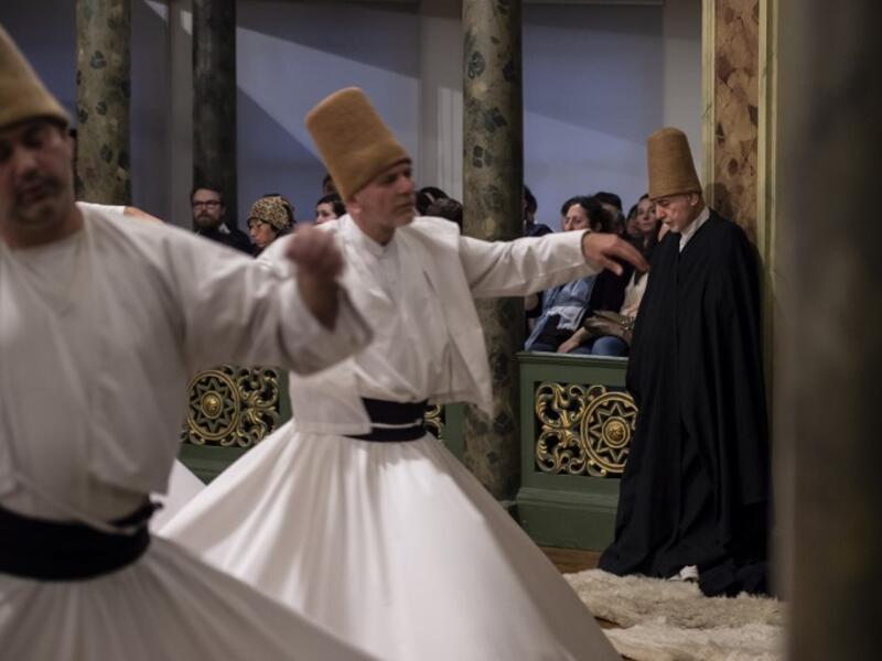 People look at whirling dervishes performing during a ceremony marking the anniversary of the death of Jelaleddin Mevlana Rumi, Sufi mystic, poet and founder of the sufism on December 16, 2018 at Galata Mevlihanesi in Istanbul. 
Yasin AKGUL / AFP