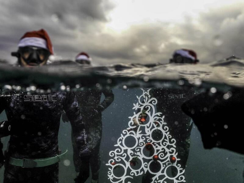 Freedivers pose with an ornamental Christas tree near the surface before diving to place it on the sea-floor off the coast of the northern Lebanese port city of Tripoli on December 18, 2018. 
IBRAHIM CHALHOUB / AFP