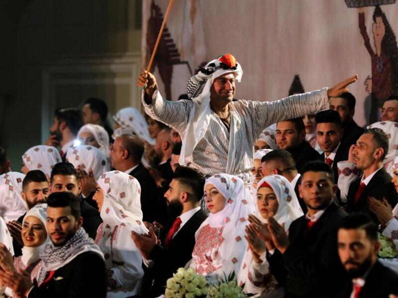 A man dressed in traditional Palestinian clothing dances during a mass wedding ceremony  
Mahmoud ZAYYAT / AFP