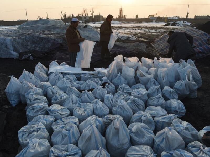 In this photograph 2019, Afghan workers fill sacks with coal at a coal yard amid heavy smog conditions in the outskirts of Kabul. 
WAKIL KOHSAR / AFP