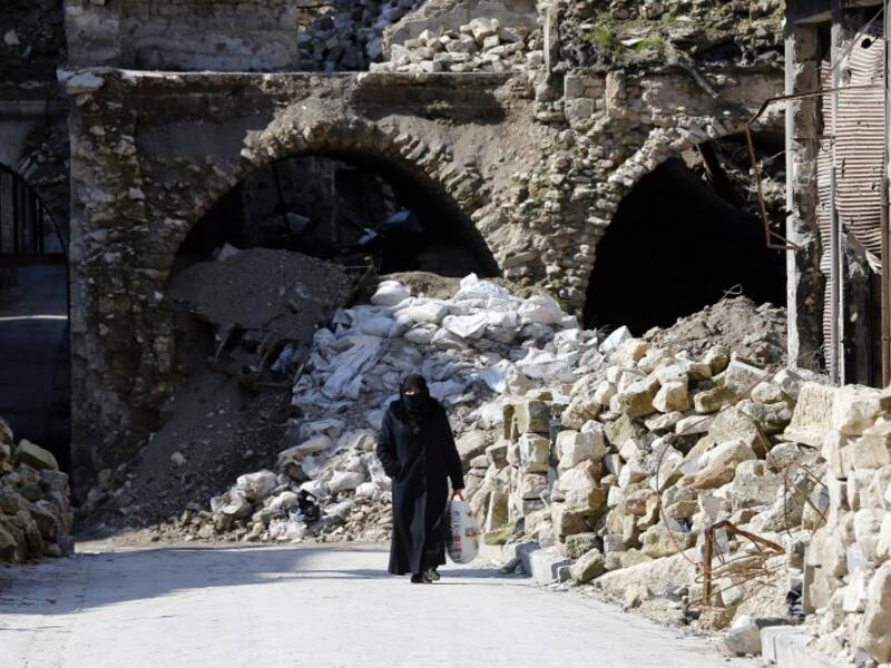 A general view shows a woman walking past debris in the old quarter of Syria's second city of Aleppo 
LOUAI BESHARA / AFP