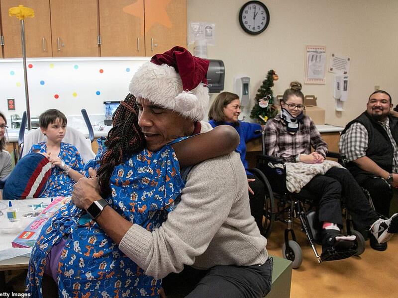 Obama hugs a girl after presenting a Christmas gift to her in the hospital in DC (AFP)