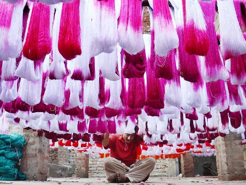 A Pakistani worker dries fabric threads after dyeing them at a factory in Lahore (Twitter)
