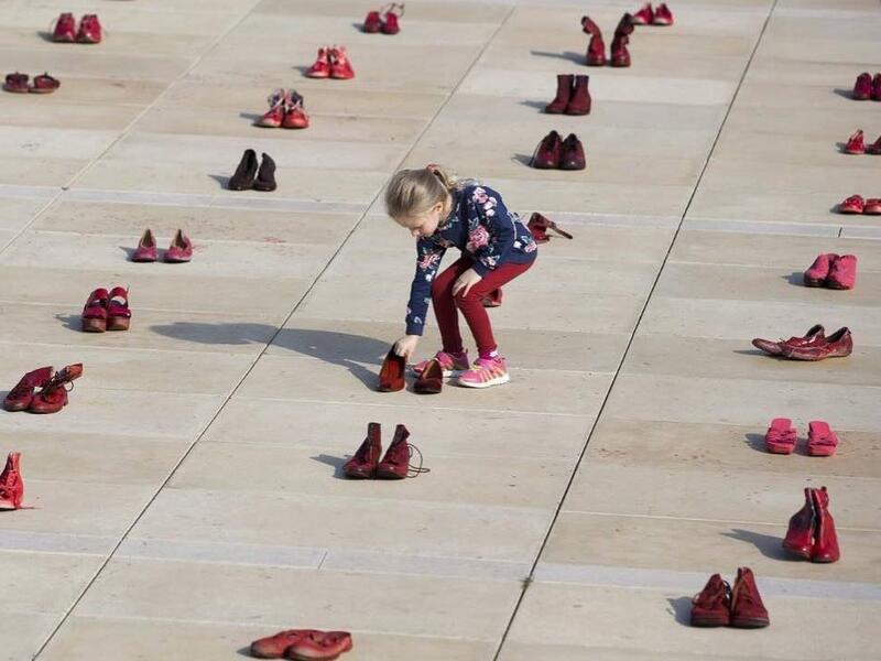 Israelis walk past an installation of red shoes during a rally against domestic violence in the Israeli coastal city of Tel Aviv on December 4, 2018 (Twitter)