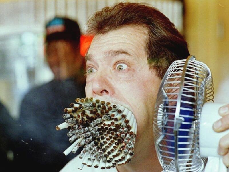 Jim Mouth uses a fan to blow smoke from 155 cigarettes as he breaks “The Guinness Book of World Records” record November 18, 1993 for smoking the most cigarettes at the same time. (AFP/ File Photo)