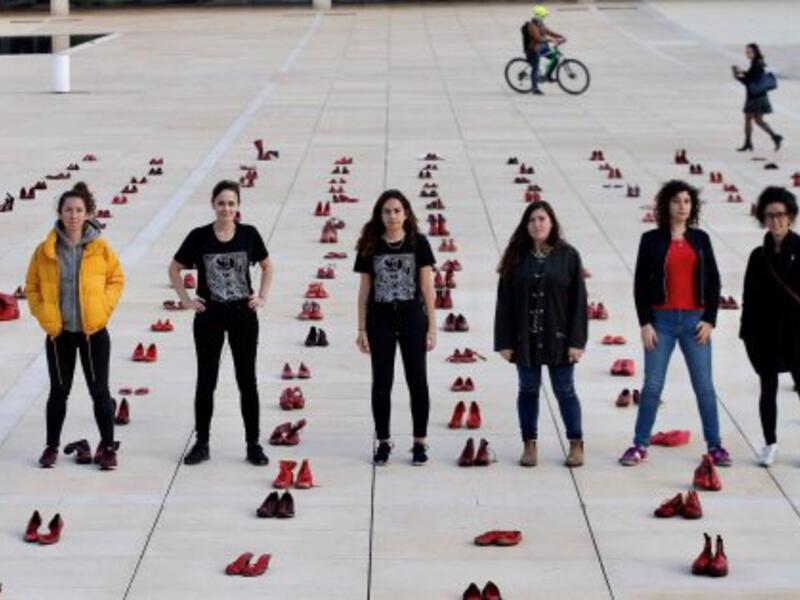 Israelis walk past an installation of red shoes during a rally against domestic violence in the Israeli coastal city of Tel Aviv on December 4, 2018 (Twitter)