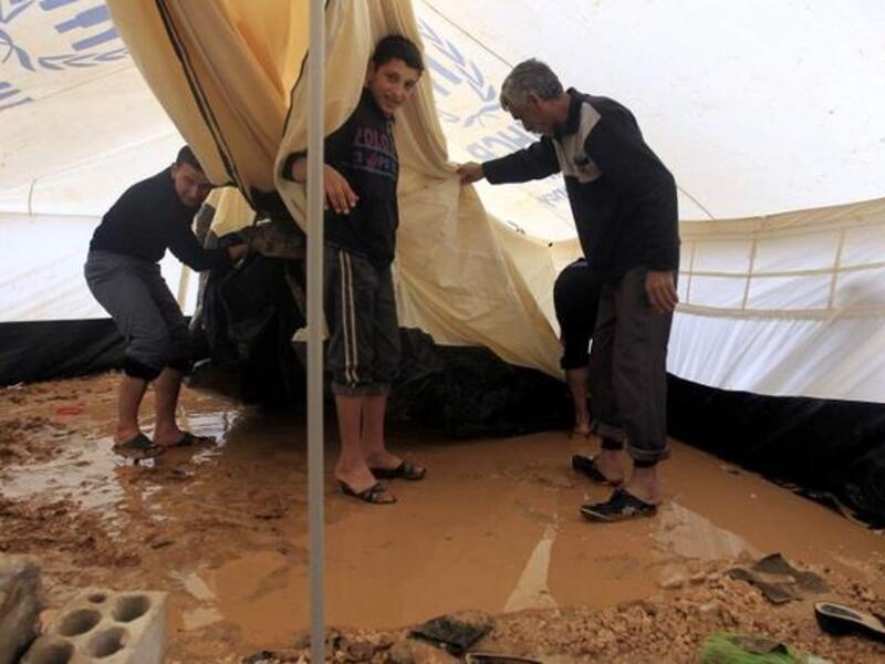 Syrian refugees try to remove water which had collected inside their tent after heavy rain in the Zaatari refugee camp. (AFP PHOTO/KHALIL MAZRAAWI)
