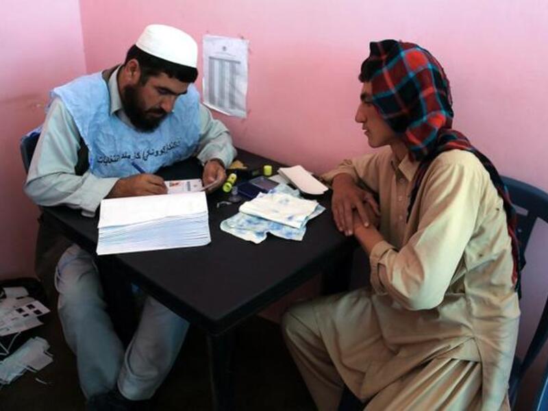 An Afghan man waits to receive his identification card to vote in upcoming elections. [AFP]