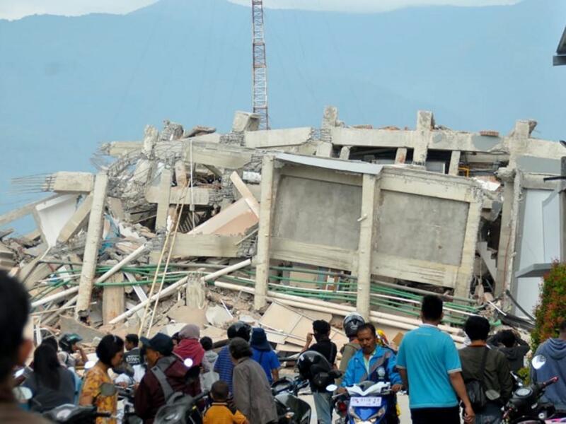 Residents gather to look at a collapsed building after an earthquake and tsunami hit Palu on Sulawesi island on September 29, 2018. (MUHAMMAD RIFKI / AFP)