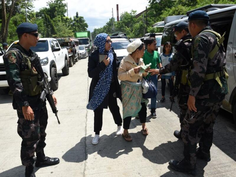 Philippine policemen check evacuees from Marawi aboard a van at a checkpoint by the entrance of Iligan City, in southern island of Mindanao on May 24, 2017. (AFP/Ted Aljibe)