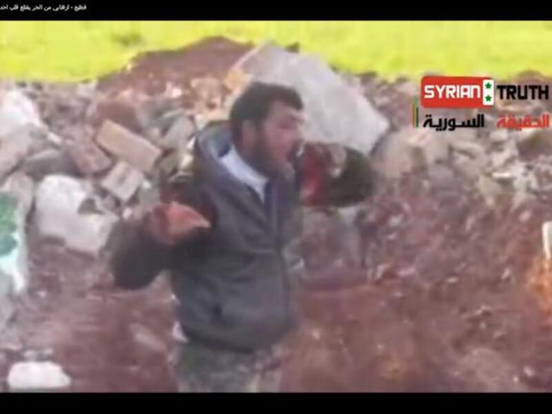 A Syrian rebel eats the heart of a dead Syrian solider.( YouTube screen-grab)