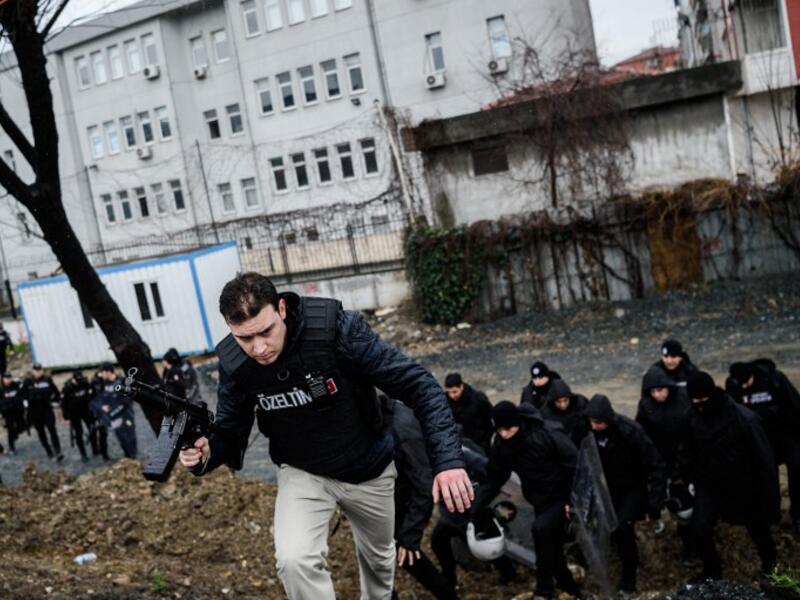 Turkish anti-riot policemen take cover during clashes with two female assailants, on March 3, 2016, in the Bayrampasa neighborhood in Istanbul, after the two women hurled grenades and opened fire at an Istanbul police station. (AFP/Ozan Kose)