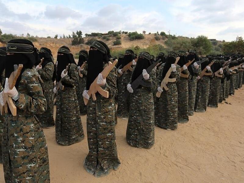 The camouflage wearing women of the outfit stand in line holding wooden rifles.  al-Quds Brigades is the military wing of Islamic Jihad, the second-most powerful armed group in the Gaza Strip after Hamas (APA)