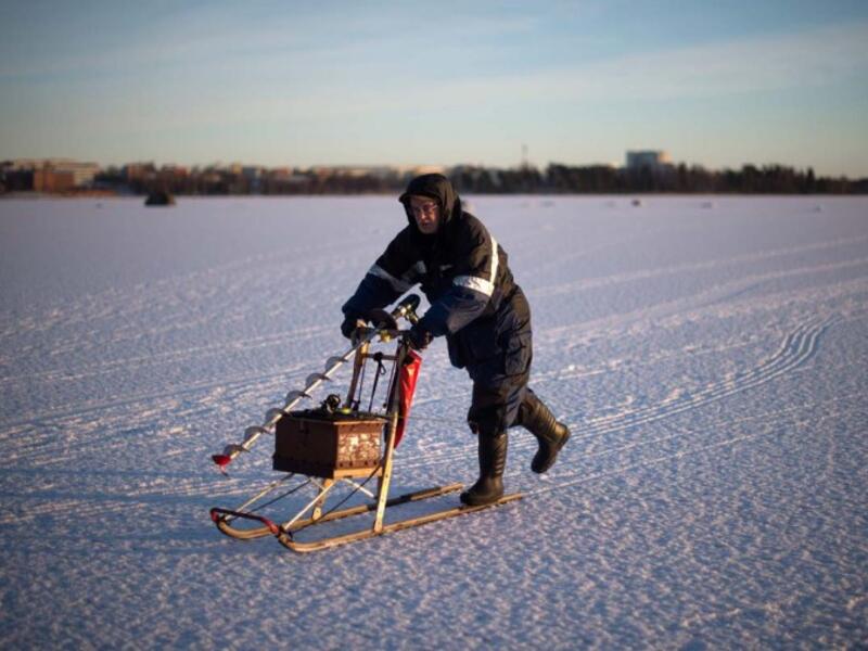 A man going ice-fishing slides on a vintage sled carrying a powerdrill and his fishing gear on the frozen Bothnia Sea, on December 28, 2016 in Vaasa, Western Finland. (OLIVIER MORIN/AFP)