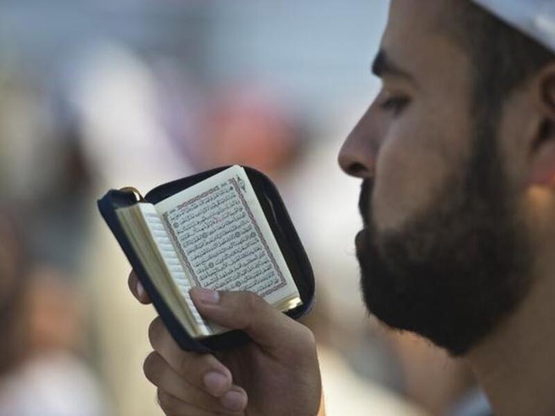 EGYPT, Cairo : A supporter of Egypt's deposed president Mohamed Morsi reads the Koran during a rally calling for his release and re-instatement outside Rabaa al-Adawiya mosque in Cairo on August 4, 2013. AFP PHOTO / KHALED DESOUKI