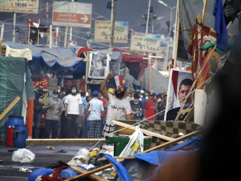 EGYPT, Cairo : A supporter of Egypt's ousted president Mohamed Morsi (portrait) shouts slogans as Egyptian security forces move in to disperse the pro-Islamist protesters by force in a huge protest camp near Rabaa al-Adawiya mosque in eastern Cairo on August 14, 2013. AFP PHOTO /MOHAMMED ABDEL MONEIM