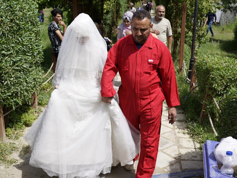 A man in prison suit in chains, next to him there is a huge gift-wrapped box, which was a woman in a wedding dress. 
Baghdad's Woman Association