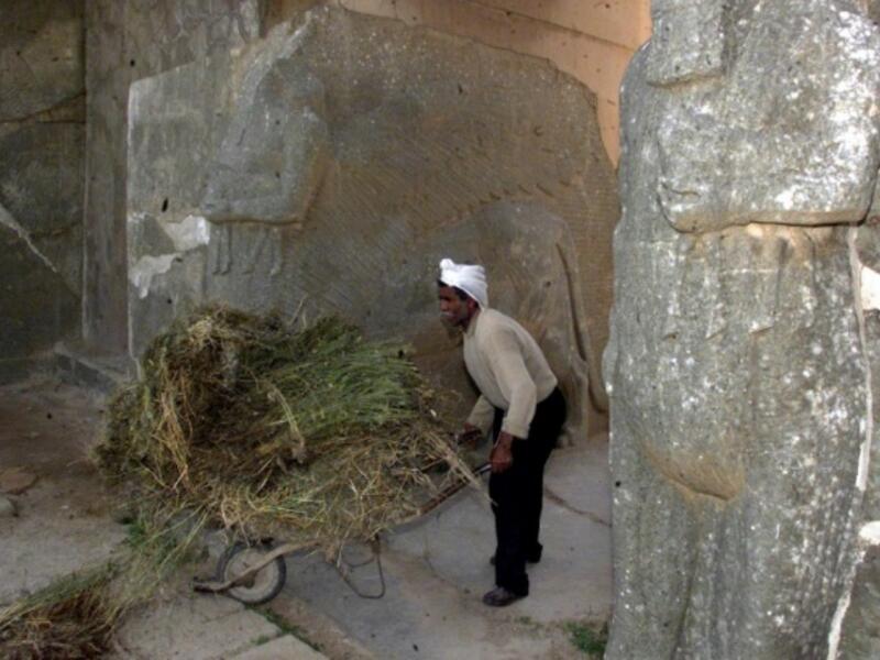 An Iraqi worker cleans up the archaeological site of Nimrud, south of Mosul in northern Iraq, 21 April 2001. (AFP/File) 