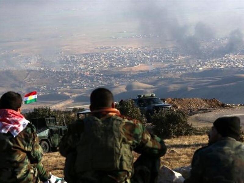 Iraqi Kurdish forces watch explosions in the distance while holding a position. (AFP/File)