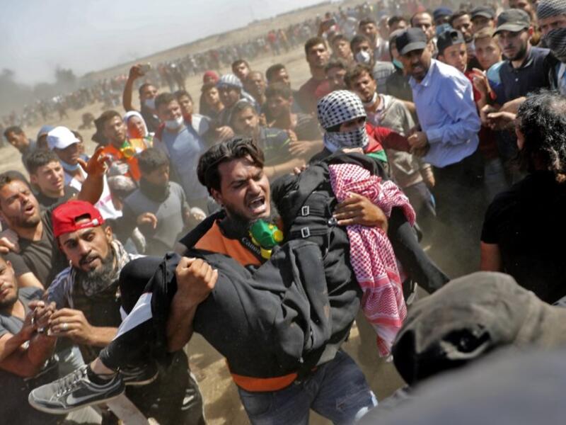 Palestinians carry a demonstrator injured during clashes with Israeli forces near the border between the Gaza strip and Israel east of Gaza City on May 14, 2018. Thomas COEX / AFP