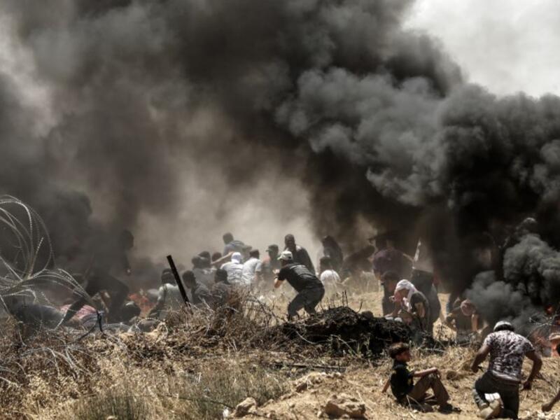 Palestinians clash with with Israeli forces near the border between the Gaza strip and Israel east of Gaza City on May 14, 2018, as Palestinians protest over the inauguration of the US embassy following its controversial move to Jerusalem. MAHMUD HAMS / AFP