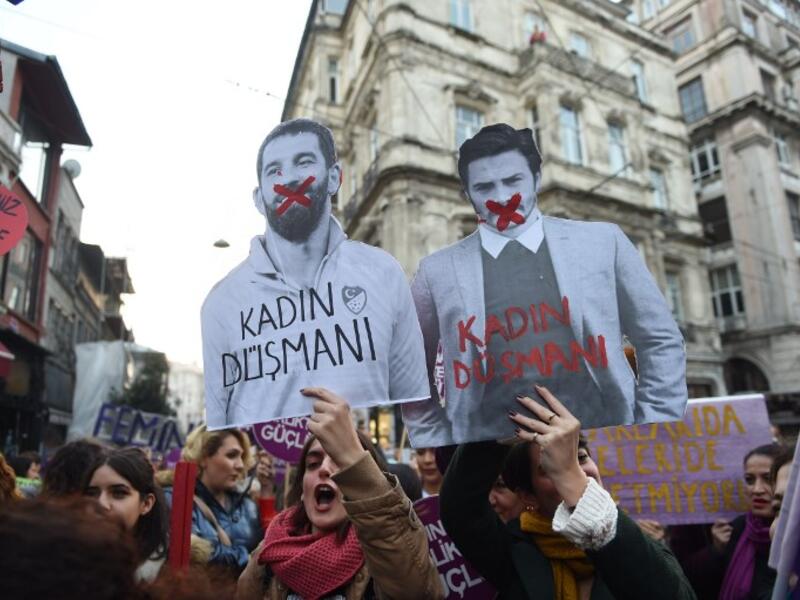 A women's rights activist holds a picture of Turkish football player Arda Turan (L) with the lettering 'Enemy of woman' as activists march through Taksim Square to protest against gender violence in Istanbul, on November 25, 2018, on the International Day for the Elimination of Violence against Women. 
BULENT KILIC / AFP