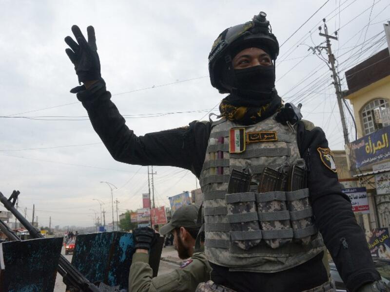 A member of the Iraqi security forces salutes onlookers as he parades in the streets of the Iraqi city of Mosul, during celebrations marking the first anniversary of the country's victory over the Islamic State (IS) group. 
Zaid AL-OBEIDI / AFP