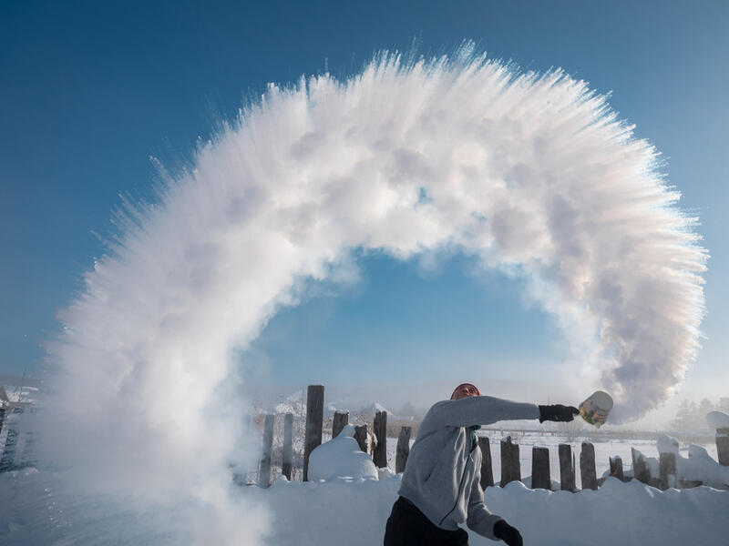 A man from the ladle pours the boiling water up into the sky in an arc in freezing weather when temperature is -48 degrees. (Shutterstock/ File Photo)