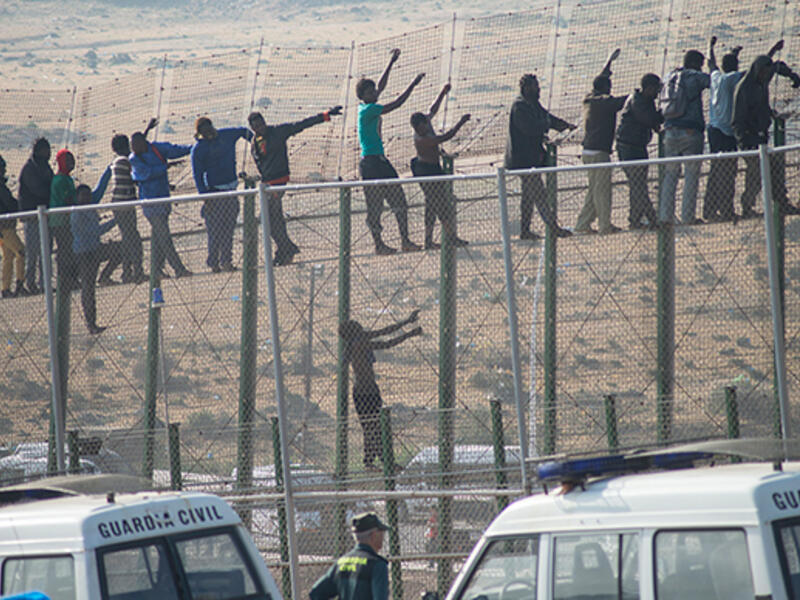Would-be immigrants stand atop a border fence separating Morocco from the Spanish enclave of Melilla on May 1, 2014, following a morning assault on the border in an attempt to cross into Spain. (AFP/File)