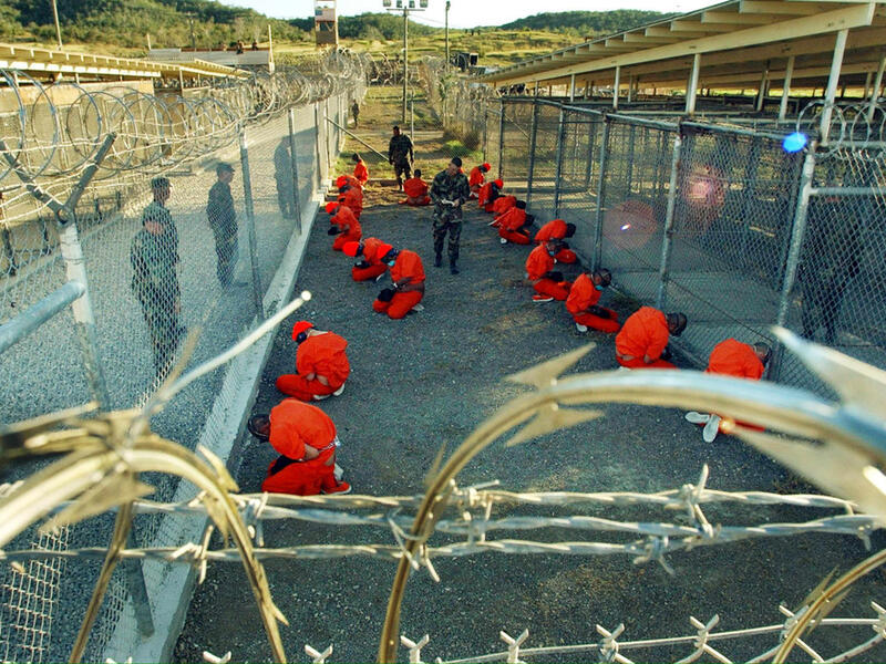 Al-Qaeda and Taliban detainees sit in a holding area under the surveillance of U.S. Military police at Camp X-Ray, a temporary prison site at Guantanamo Bay. (AFP/File)