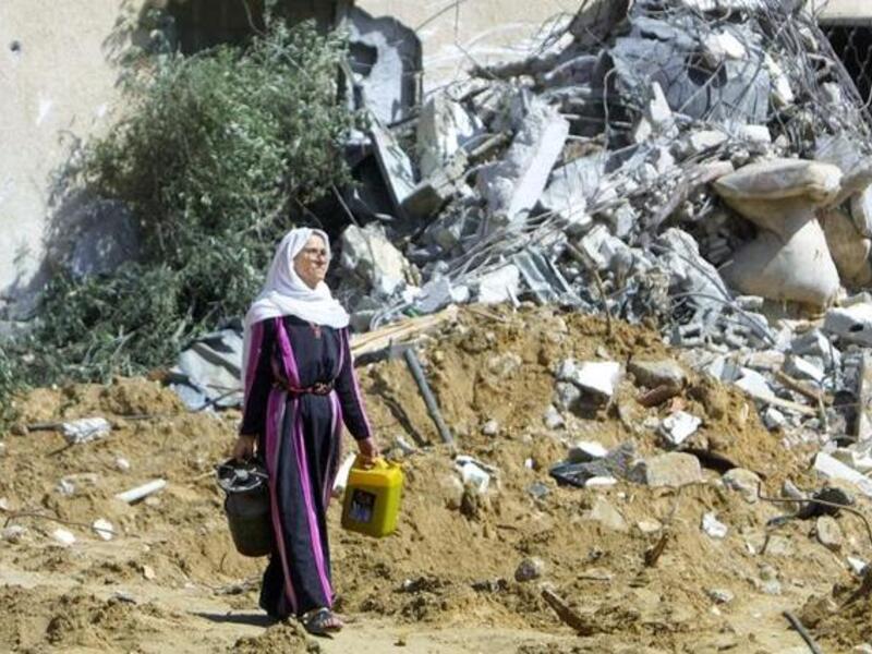 A Palestinian woman leaves what once was her home carrying a gas cooker after her house was bulldozed by the Israeli Army, a practice Human Rights Watch says could be war crime. (AFP/Said Khatib)